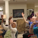 Seniors seated in chairs doing yoga